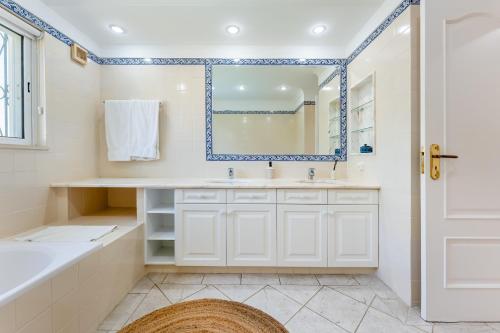 a bathroom with a tub and a sink and a mirror at Villa Mia - Vale do Lobo in Vale do Lobo