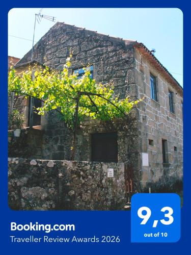 a tree in front of a stone building at Casa Vouzelinha in Vouzela