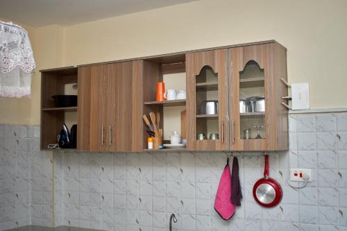 a kitchen with wooden cabinets and a red spatula at Deluxe Homes 2, Voi in Voi