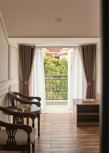 a room with a table and chairs and a balcony at Hill Side Town Hotel DaLat in Da Lat