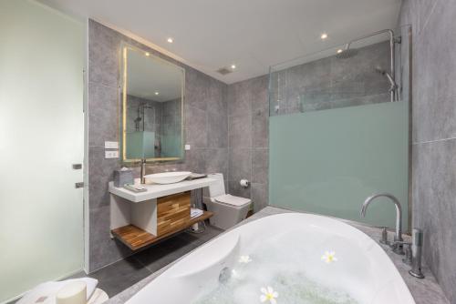 a bathroom with a tub and a sink and a mirror at UniQue BoutiQue Resort in Bangrak Beach