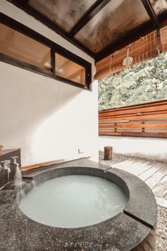 a large bath tub in a room with a window at Chiangrai Ryokan in Ban Long Khi Na