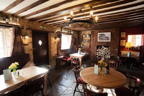 Un restaurante con mesas y sillas de madera en una sala. en The Bluebell, en Helpston