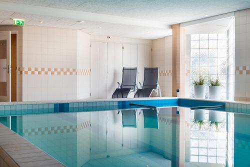 una piscina con due sedie in un edificio di Paping Hotel & Spa - Rest Vonck by Flow a Ommen