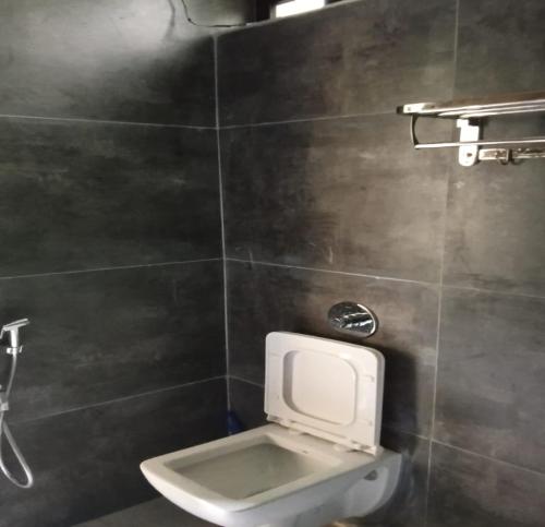 a bathroom with a white toilet in a tiled wall at Kodai Elegance in Kodaikānāl