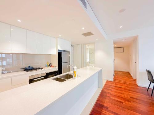 a kitchen with white cabinets and a wooden floor at Burwood Grand Service Apartment in Sydney