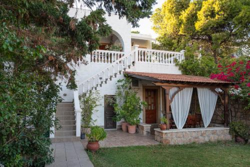 a white house with a staircase and flowers at Irene Studios Patmos in Skala