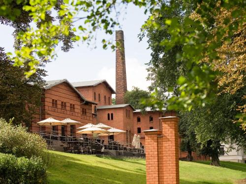 an old brick building with umbrellas and a smoke stack at Landgut Stober in Groß Behnitz
