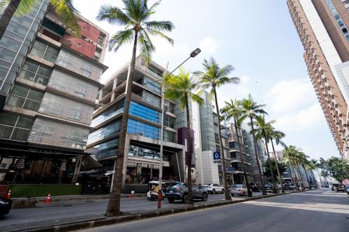 a street with palm trees and a tall building at Spacious 3BR near Impact, Don Mueang Airport & Pink Line MRT in Nonthaburi