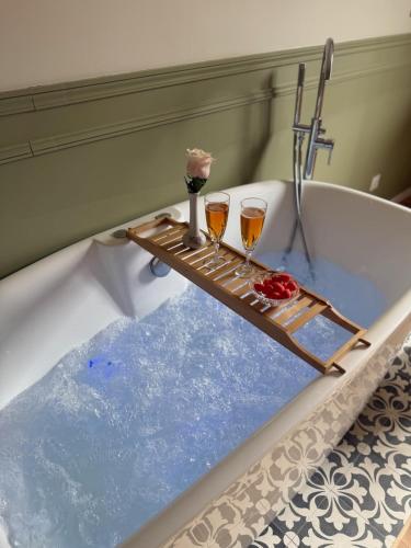 a bath tub with two wine glasses in it at L Entre Deux Époques in Pré-en-Pail