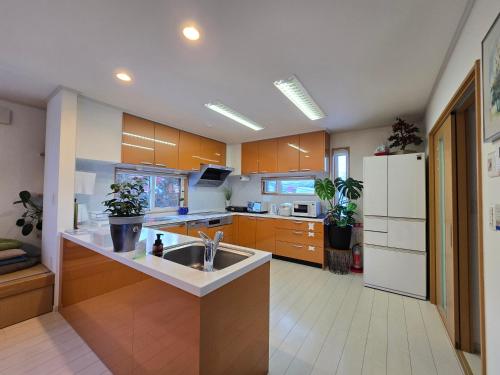 a kitchen with a sink and a white refrigerator at Hokkaido Hakodate Onuma National Park Kenzo's House in Ōnuma