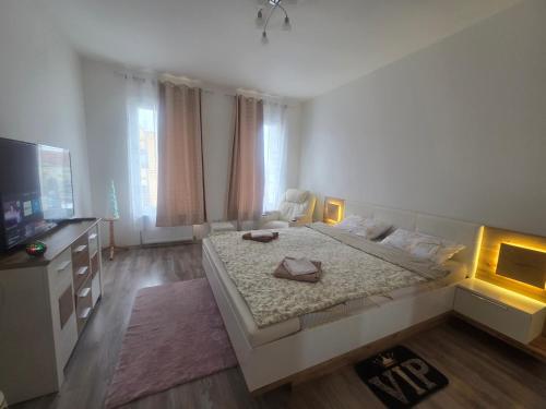 a white bedroom with a large bed and a flat screen tv at 3 Apartments Angels o k b in Altenburg
