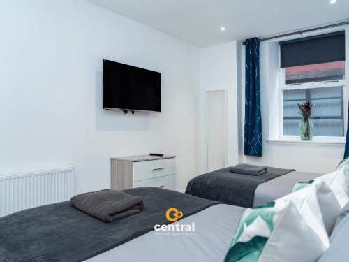a bedroom with two beds and a flat screen tv at The Bond by CENTRAL SERVICED APARTMENTS - 2 Bedrooms - 3 Double Beds - Walk Away From City Centre & Universities - Walk away from Bus & Train Station & Waterfront - Short & Long Stays Accomodated in Dundee