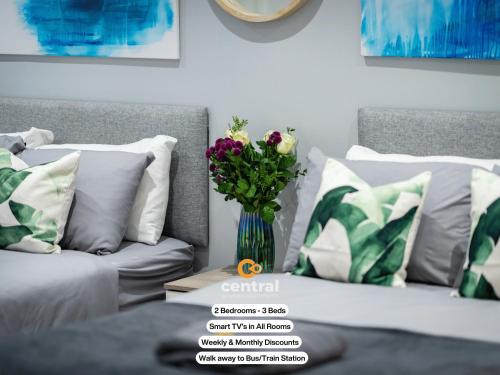 a vase of flowers sitting on a table next to a couch at The Bond by CENTRAL SERVICED APARTMENTS - 2 Bedrooms - 3 Double Beds - Walk Away From City Centre & Universities - Walk away from Bus & Train Station & Waterfront - Short & Long Stays Accomodated in Dundee