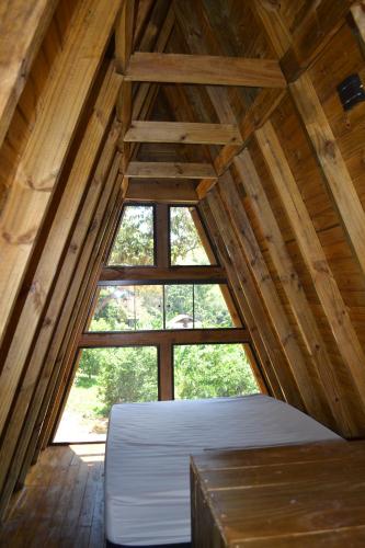 an attic room with a bed and a window at Chalé Pé da Serra - Região de Monte Verde in Camanducaia