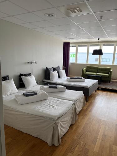 a room with three beds and a green couch at Hotell Fyrislund in Uppsala