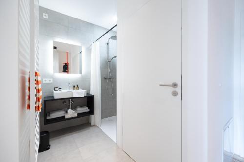 a white bathroom with a sink and a mirror at Coho Slowliving in Linz