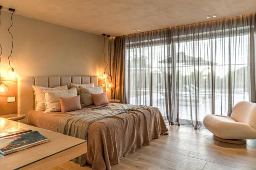 a bedroom with a large bed and a chair at Villa Pefkos Shore by Villa Plus in Pefki