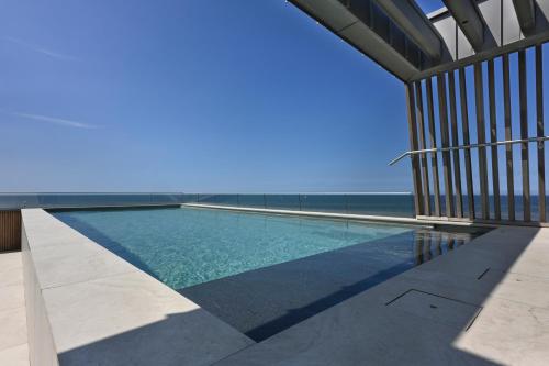 a swimming pool with the ocean in the background at Boutique Hotel Blendin Bloemendaal aan Zee in Bloemendaal Aan Zee
