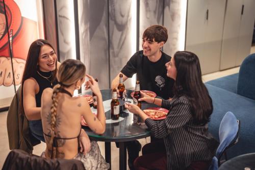 a group of people sitting around a table with food at Coeo Pod Hostel Beatas in Málaga