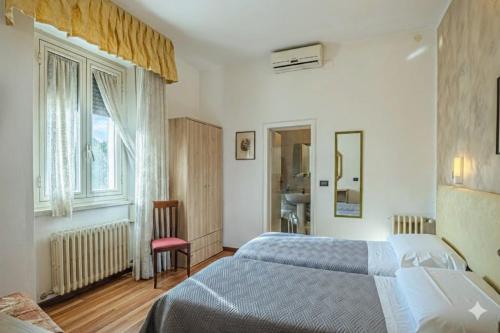 a bedroom with a bed and a chair and a window at Hotel Paradiso in Monteluco
