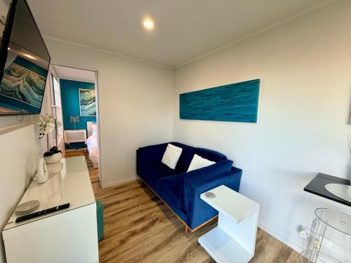 a living room with a blue couch and a table at Tiny House in Belconnen 1BR Self Contained Complete Home Filtration as seen on The Block Phillip Island Wine in Higgins