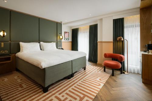 a bedroom with a large bed and a red chair at Carlton George Hotel in Glasgow
