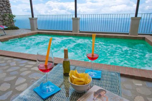 a pool with two glasses of wine and a bowl of chips at House Teresa - private pool in Praiano