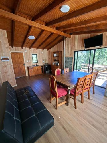 a dining room with a wooden table and chairs at cabaña los ulmos in Lago Ranco