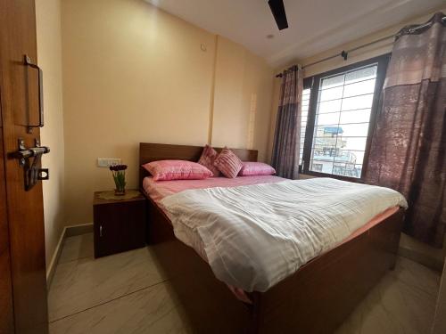 a bedroom with a bed with pink pillows and a window at Uttarayan The Homestay in Almora