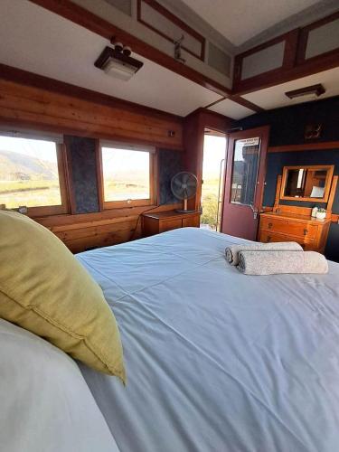 a large white bed in a room with windows at The Red Caboose Train Carriage in McGregor