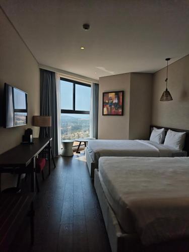 a hotel room with two beds and a desk at Apec Mandala Sea View Bathtub by MLT in Mui Ne