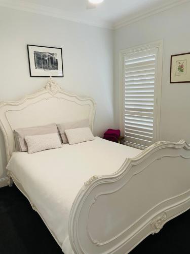 a white bed with two pillows in a bedroom at Bowral Retreat in Bowral