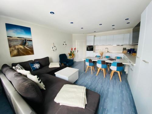 a living room with a black couch and a kitchen at Kieferneck Ferienwohnung Hedi in Karlshagen