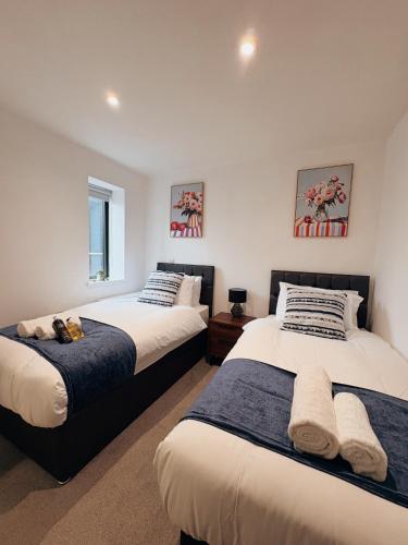 two beds in a bedroom with white walls at Two Bedroom Warm and Cozy Retreat in Exeter in Exeter