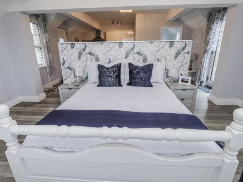 a white bed with blue pillows in a bedroom at The Wren in Colwyn Bay
