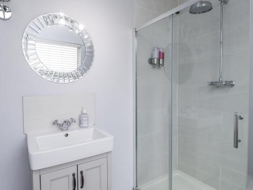 a bathroom with a shower and a sink and a mirror at The Wren in Colwyn Bay