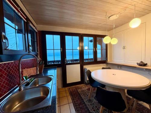 a kitchen with a sink and a table with chairs at Chalet Apartment Faulensee in Faulensee