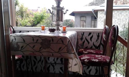 a table and chairs on a balcony with a table and a window at Ilgar's Hostel in Sheki