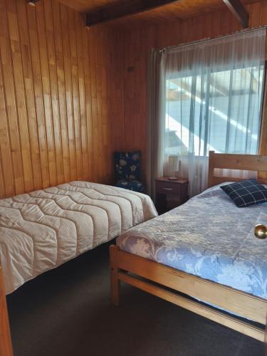 a bedroom with two beds and a window at Astilleros,Dalcahue in Dalcahue