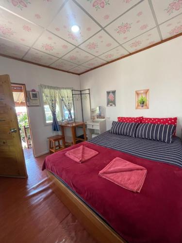 a bedroom with a large bed with red sheets at Yada homestay in Ban Bu Lu