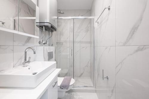 a white bathroom with a shower and a sink at Delfini Girni Apartments in Paralia Katerinis
