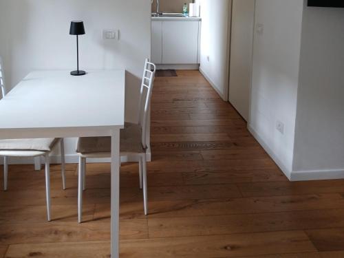 a white dining room table and chairs on a wooden floor at Il monolocale in Bosisio Parini