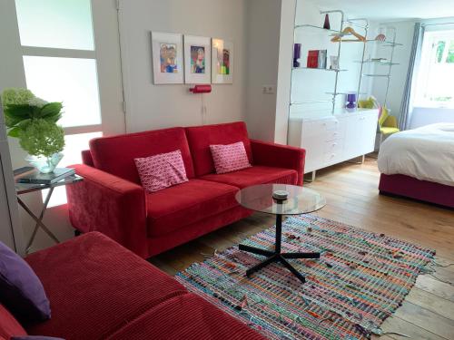 a living room with a red couch and a table at Luxury guesthouse - Eik bij de dijk in Aalst