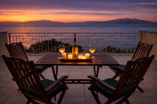 a table with two chairs and a bottle of wine at Derveni Seaside Apartments - Deluxe Sea View Penthouse Jacuzzi-BBQ & Groundfloor Garden View Apartment in Derveni