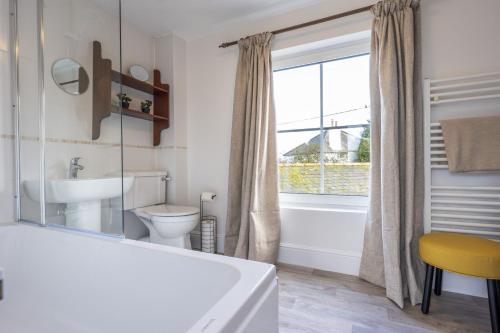 a bathroom with a tub and a toilet and a window at Hatchet Pond Cottage in Beaulieu