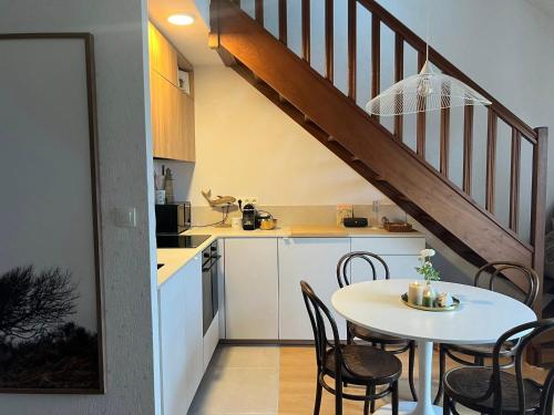 a kitchen and dining room with a table and a staircase at Entre Mer et Dunes de Pin in Neufchâtel-Hardelot