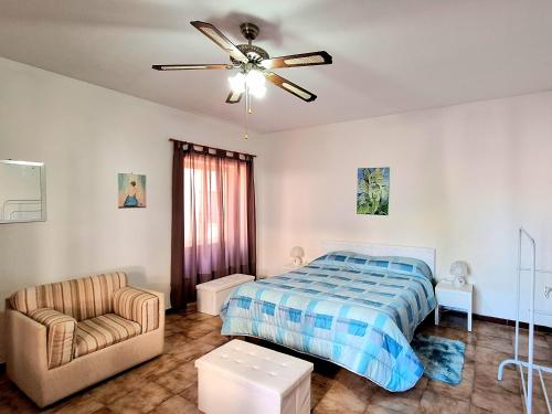a bedroom with a bed and a chair and a ceiling fan at Mare&Monti Guest House with Private Parking in Telti