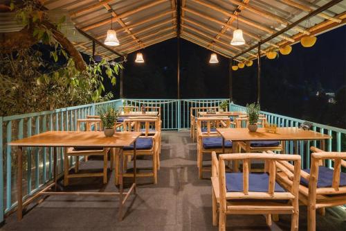 a restaurant with wooden tables and chairs on a balcony at havana stays in Jibhi