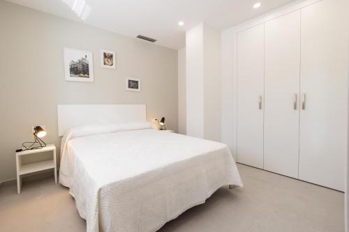 a white bedroom with a bed and a white cabinet at Iberflat Apartamentos Alfabega in Paterna